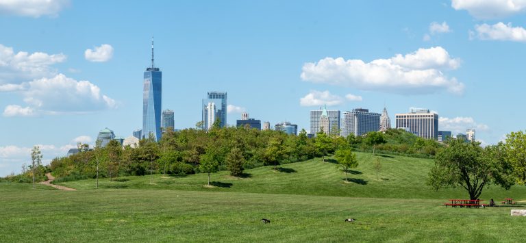The lawns and hills of Governors Island with the Lower Manhattan skyline behind