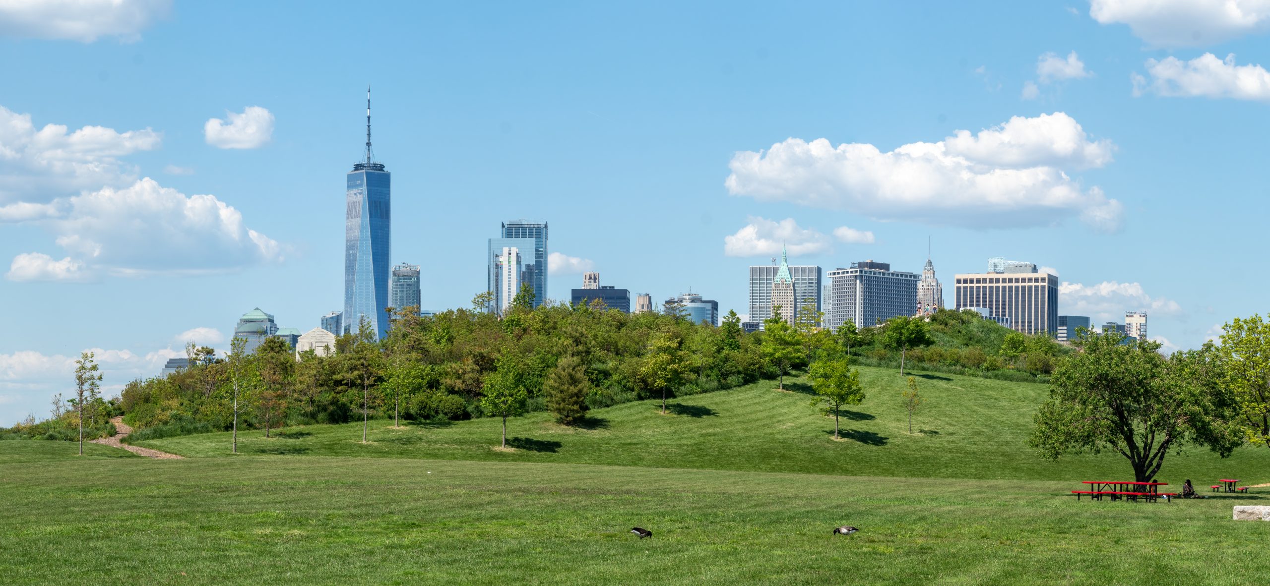 The lawns and hills of Governors Island with the Lower Manhattan skyline behind